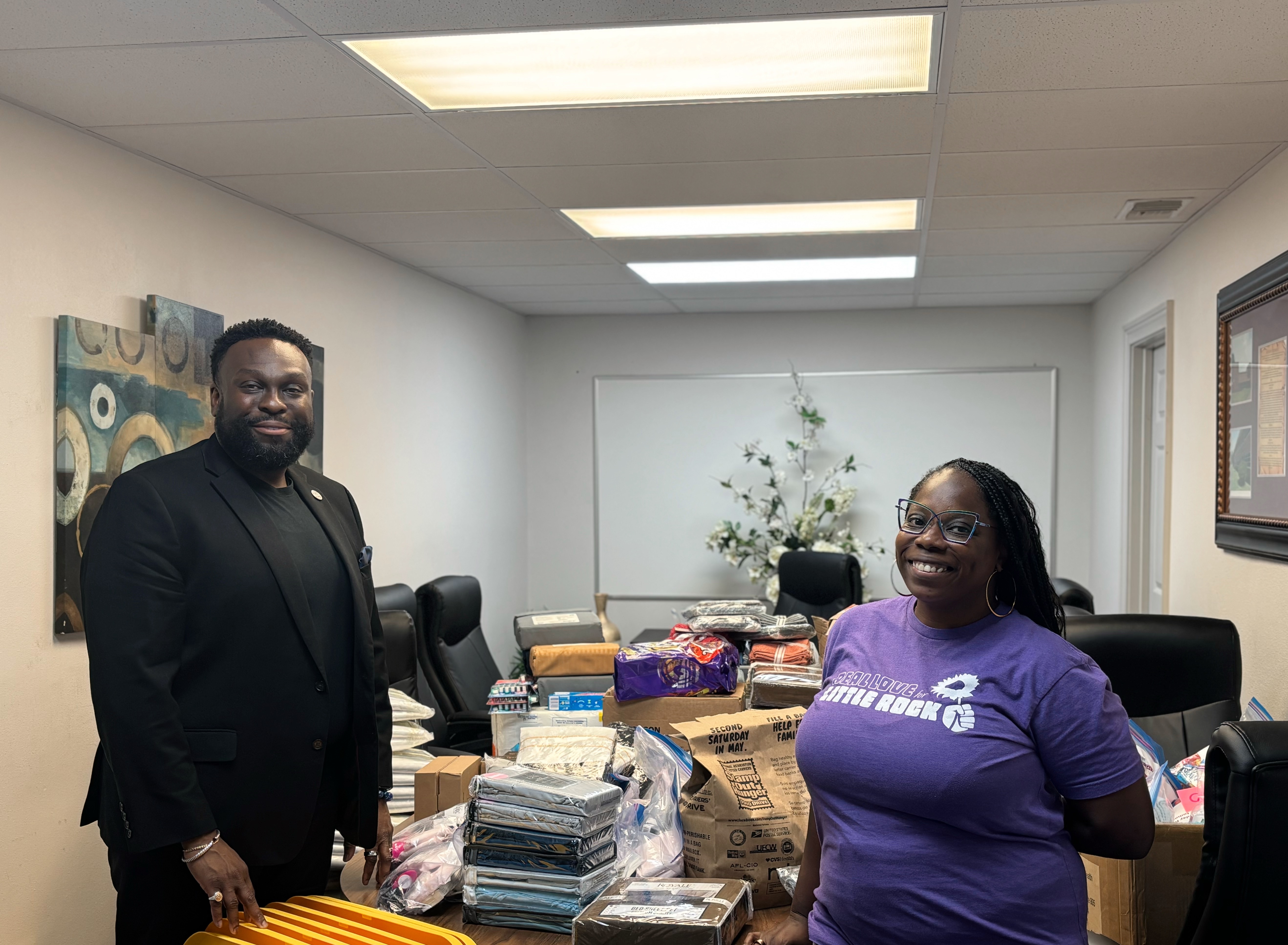 A Rocktown Realness organizer and a Shorter College representative beside a table of donated bedding and supplies